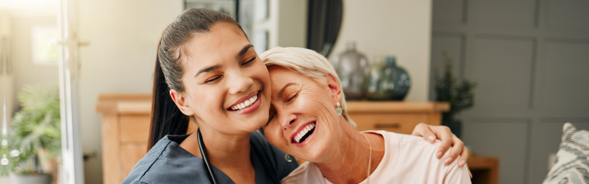 Nurse hugging an elderly woman and both smiling
